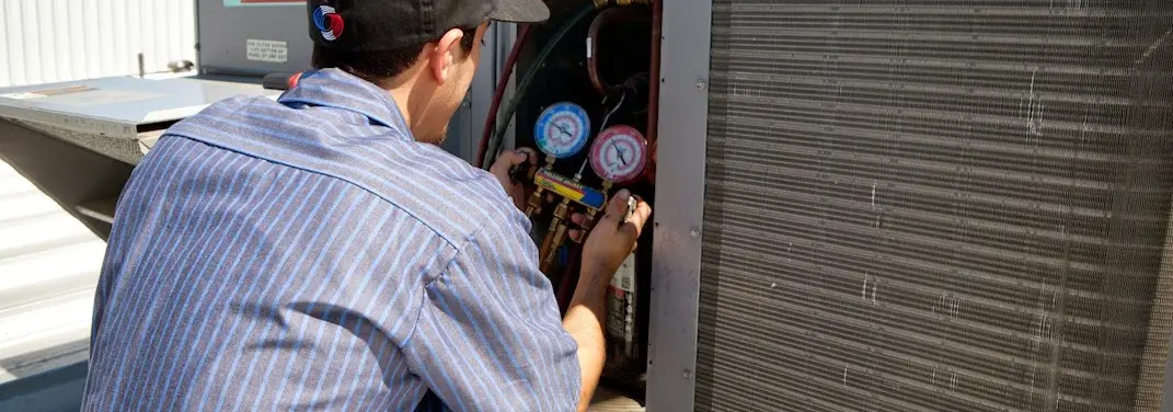 HVAC technician servicing a condenser unit in Stow